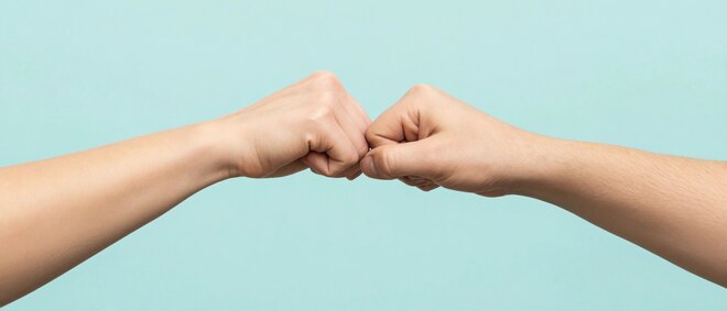 Close up shot of couple two male friends men together hold hands folded fist bump gesture isolated on pastel plain light blue cyan color background studio portrait. 