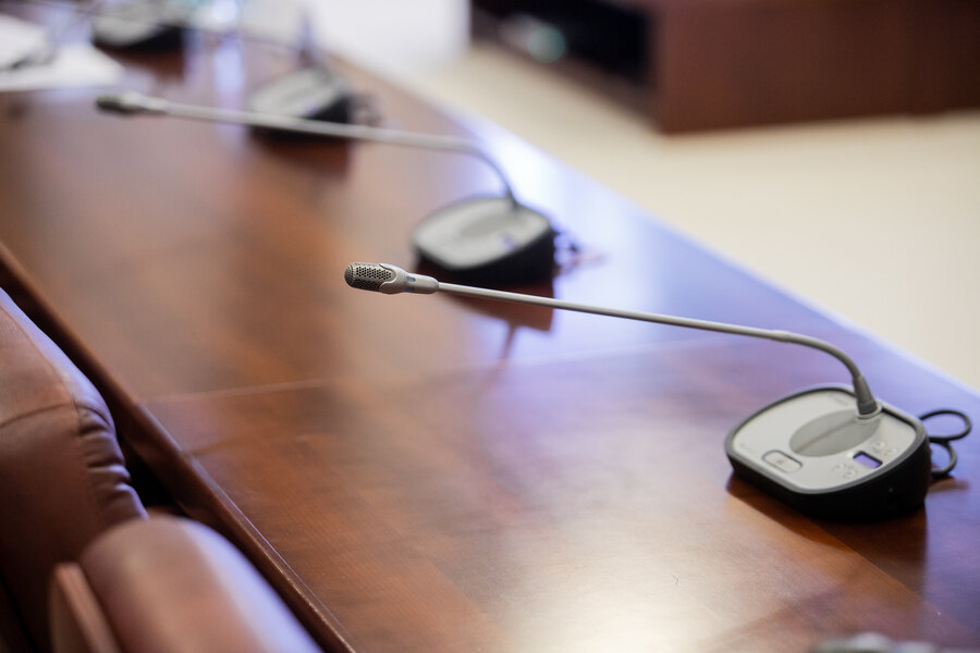 Vier Mikrofone auf einem Konferenztisch in einem modernen Besprechungsraum