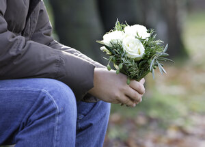 Trauer Mann mit einem Blumenstrauss im Herbstwald 