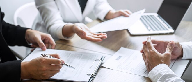 Employer or committee holding reading a resume with talking during about his profile of candidate, employer in suit is conducting a job interview