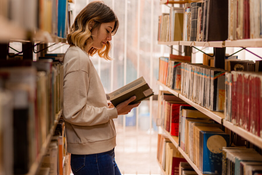 Studentin liest in Bibliothek