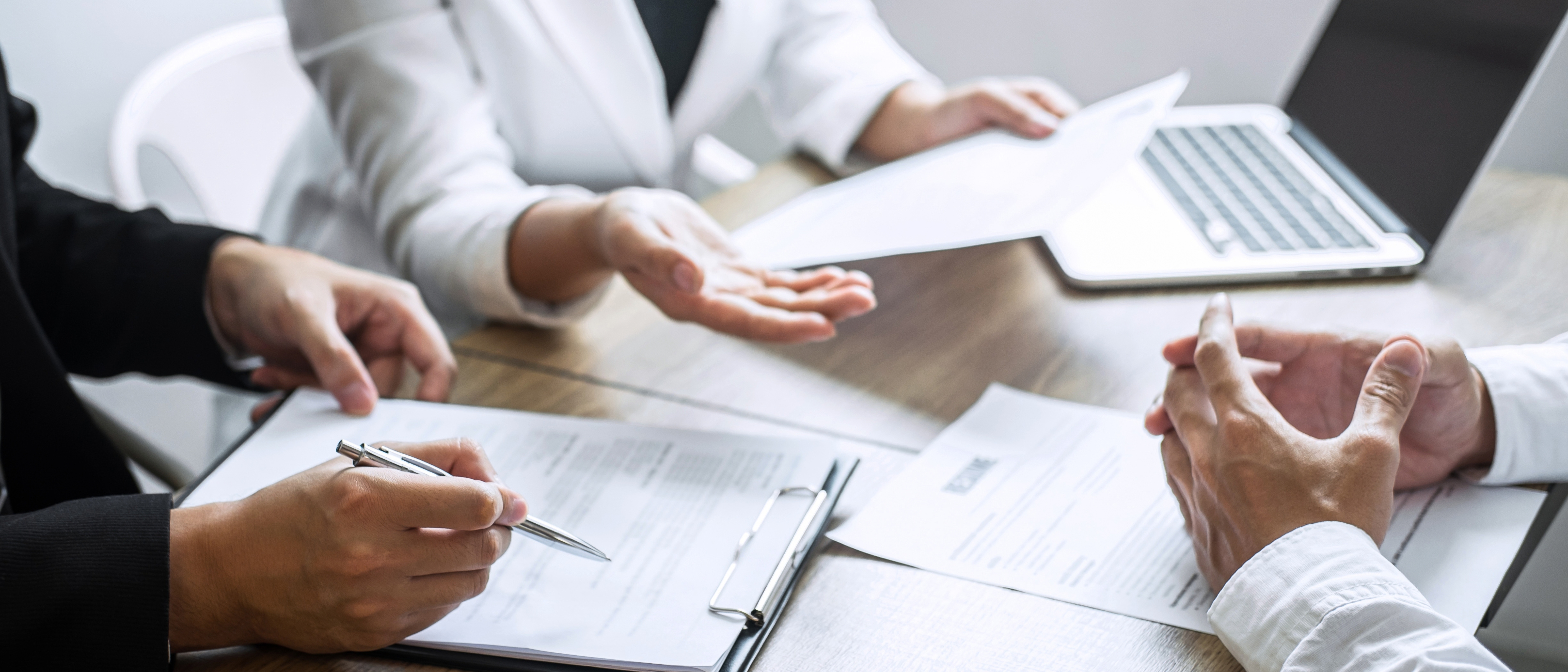Employer or committee holding reading a resume with talking during about his profile of candidate, employer in suit is conducting a job interview