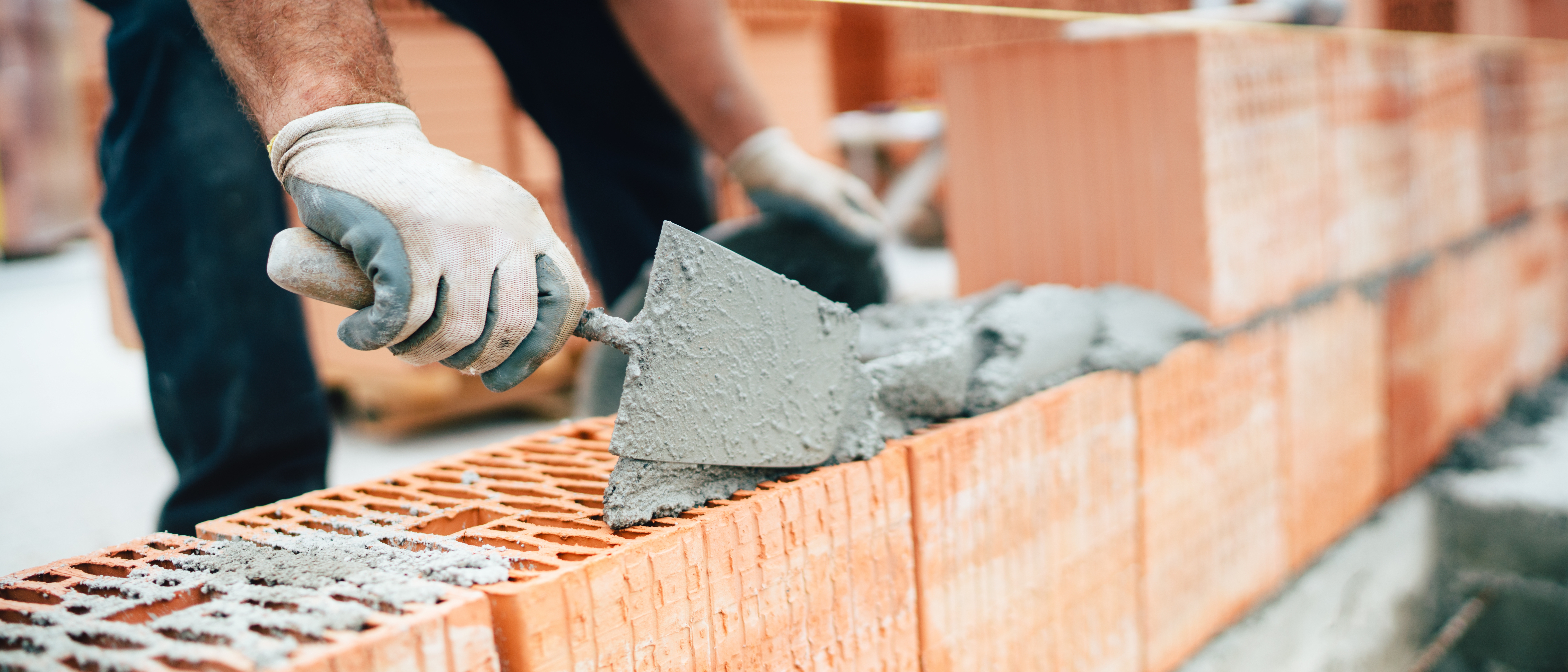 Professional worker using pan knife for building brick walls with cement and mortar 